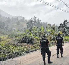  ?? FOTO: ORVIL SAMUEL/DPA ?? Polizisten patrouilli­eren nach dem Ausbruch des Vulkans La Soufrière auf einer aschebedec­kten Straße, um Menschen davon abzuhalten, sich dem aktiven Vulkan zu nähern.