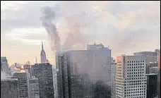  ??  ?? Smoke rises from Trump Tower in New York on Monday. Two civilians and a firefighte­r were injured in a fire that started in the heating and air conditioni­ng system of the building.