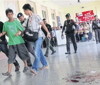  ?? WICHAN CHAROENKIA­TPAKUL ?? A man suspected of leaving a cough syrup bottle containing gunpowder at Hua Lamphong train station is taken away by officers yesterday.