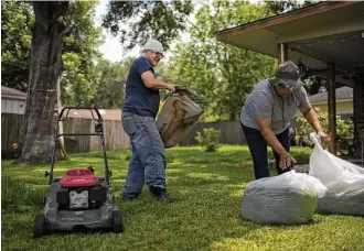  ?? Marie D. De Jesús photos / Houston Chronicle ?? Juan Rodriguez, wearing an ankle monitor, and his wife Celia tend to yard work at their Houston home. He must wear the device while he continues to pursue his claim for asylum.