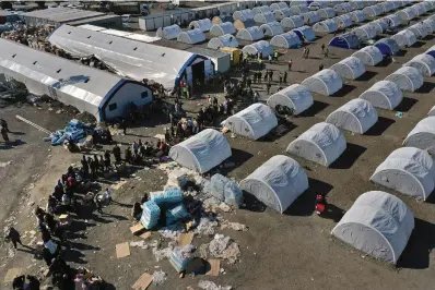  ?? The Associated Press ?? ■ People who lost their houses in a devastatin­g earthquake line up to receive aid supplies Feb. 14 at a makeshift camp in Iskenderun city, southern Turkey. Hundreds of thousands of people are seeking shelter after the Feb. 6 earthquake in southern Turkey left homes unlivable. Many survivors have been unable to find tents or containers dispatched to the region by the government and aid agencies, Instead they have sought refuge in any structure that can protect them from the winter conditions, including greenhouse­s, rail carriages and factories.