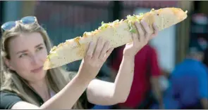  ?? The Canadian Press ?? A woman uses both her hands to hold up the two-foot-long taco from the vendor Machette, during the media preview event for the Canadian National Exhibition in Toronto.