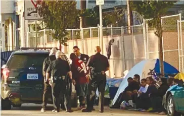  ??  ?? Harbor Division police officers with the Los Angeles Police Department attempting to help one of the houseless neighbors on Beacon Street in San Pedro. Courtesy of the office of Councilman Joe Buscaino