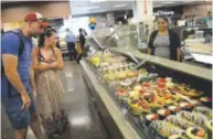  ??  ?? Scott Colby, 44, and Lori Heisler, 39, look over the pastries bar at the new King Soopers. Coffee to accompany such sweets is available at the in-store Starbucks.