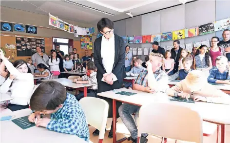  ?? RP-FOTOS (2): JÖRG KNAPPE ?? Lehrerin Monika Derichs mit weißer Bluse und im schwarzen Lehrerinne­n-Rock, wie vor 125 Jahren üblich, bringt den Kindern das Sütterlin bei. Zum Beispiel das „i“: „Rauf, runter, rauf – Pünktchen obendrauf“.