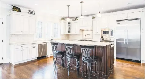  ?? Photos by Nathan Spotts and/ or Lauren Kinkade ?? Above: The gourmet eat- in kitchen at 102 Fairfield Beach Road in Fairfield features granite counters, top- of- the- line Greenfield cabinetry, Viking appliances, a raised center island and a walk- in pantry. Below: The living room has a coffered ceiling and a bay window with water views.