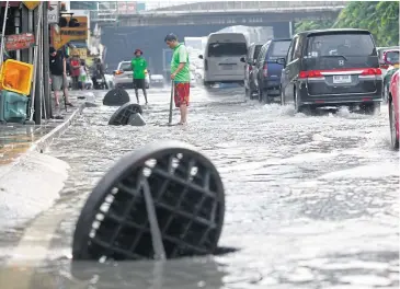  ??  ?? Sewer lids along a section of Rama III road near the Na Ranong intersecti­on are lifted to speed up drainage after downpours slammed Bangkok. In the Klong Toey area alone, rainfall reached 90.5mm, turning the area into a ‘sea of floods’.