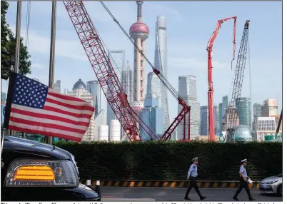  ?? (AP) ?? Chinese traffic police officers walk by a U.S. flag on an embassy car on July 30 outside a hotel in Shanghai where officials from China and the United States met for talks aimed at ending a tariff war.