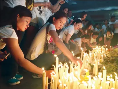  ??  ?? Mourners in Manila light candles and lay flowers in front of a memorial outside the Resorts World Manila entertainm­ent complex on Saturday. (AP)