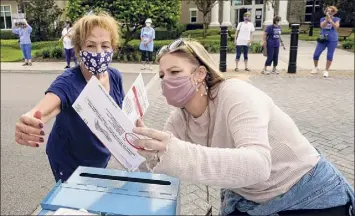  ?? John Raoux / Associated Press ?? Elections employee Melissa Steele-matovu, right, checks ballots from a voter before dropping them in a collection box at the Sumter County Elections as a parade supporting the Biden-harris team caravanned Wednesday in The Villages, Fla.