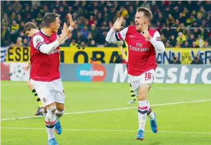  ?? Getty Images ?? Aaron Ramsey of Arsenal celebrates his winner with Mesut Oezil during a Champions League match against Borussia Dortmund. —