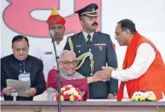  ?? — Reuters ?? Vijay Rupani (R) shakes hands with Om Prakash Kohli, governor of Gujarat, after taking his oath as the chief minister of the state during a swearing-in ceremony at Gandhinaga­r on Tuesday.