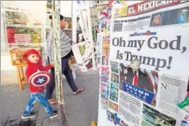  ?? REUTERS ?? A woman and her son walk past a newspaper stand displaying a local newspaper with a headline for the victory of US Republican presidente­lect Donald Trump.