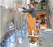  ?? MIKE DE SISTI / MILWAUKEE JOURNAL SENTINEL ?? Jimmy Gohsman, City Lights Brewing brewmaster, pulls a sample of the Amber Ale from a fermentati­on tank.