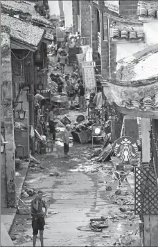  ??  ?? Left: Residents of Ziyang Old Street in Linhai clear up after the typhoon. residents left stranded on a flooded street after the typhoon hit Taizhou, Zhejiang.