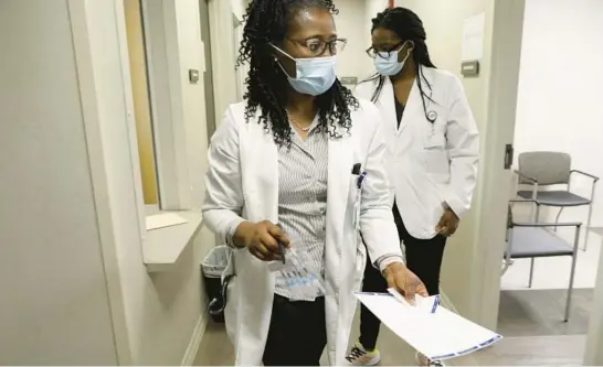  ?? ANTONIO PEREZ/CHICAGO TRIBUNE PHOTOS ?? Pharmacy manager Marian Ohale, left, prepares to administer a COVID-19 booster shot at St. Bernard Hospital and Health Care Center in Chicago on May 26. Once the booster was available, 43.9% of Black adults rolled up their sleeves for the jab, compared with 47.3% of white adults.