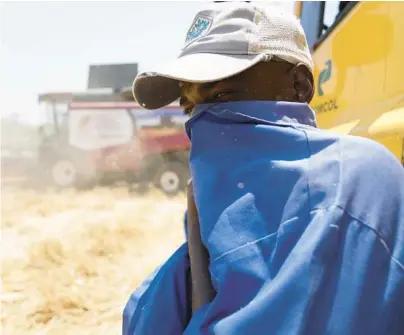  ?? TSVANGIRAY­I MUKWAZHI/AP ?? A man covers his face from the dust of a wheat harvesting operation Oct. 10 in Bindura, Zimbabwe.