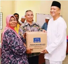  ??  ?? Lending a hand: Nazri presenting a contributi­on to a villager in Sauk near Padang Rengas.