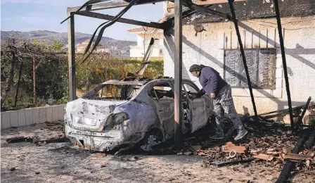  ?? MAJDI MOHAMMED AP ?? A Palestinia­n man inspects a burnt car, saying it was set on fire by Jewish settlers, in the village of Turmus Ayya in the West Bank.