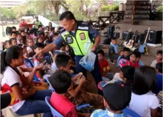  ?? Photo by Milo Brioso ?? POLICE SERVICE. Baguio City Police Office(BCPO) public city relations chief superinten­dent Armando Gapuz distribute candies to children after a lecture on crime prevention during the Police Natin Caravan at Melvin Jones grounds.