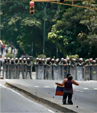  ??  ?? Manifestan­te ajoelha em frente a barreira da Guarda Nacional em avenida de Caracas