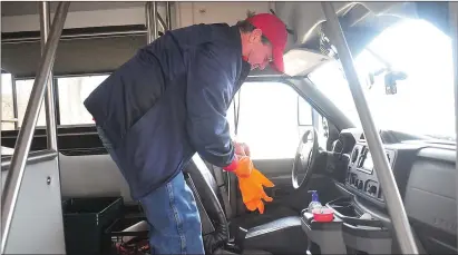  ?? Photo by Ernest A. Brown ?? Jack Stuart, senior van driver for the Blackstone and Bellingham Senior Centers, dons gloves before cleaning down the senior van outside the Blackstone Senior Center.