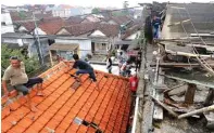  ?? BOY SLAMET/JAWA POS ?? KERUSAKAN KECIL: Wariso (kiri) melihat atap rumahnya. Sementara itu, Mohammad Yasin (kanan) mengecek atap rumahnya yang porak poranda.