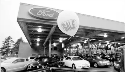  ??  ?? A balloon promotes a sale on a pickup truck Thursday at a Ford dealership in Tacoma, Wash. Ford sales fell 15 percent in November.