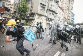  ?? Eric Tsang / HK01 ?? A protester flees from batonwield­ing police officers in the Yuen Long district of Hong Kong. The northern neighborho­od is where 45 demonstrat­ors were injured in an attack last weekend.