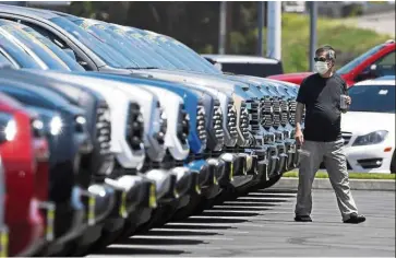  ?? — AP ?? Lower profit: A customer looking at trucks at a Toyota dealer in California. Toyota forecast operating profit of Us$4.66bil for the year through March 2021.