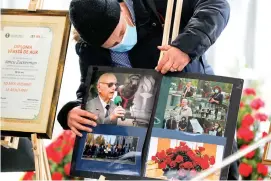  ?? The Associated Press ?? A man adjusts images of Iancu Tucarman during Tucarman’s funeral Monday at a Jewish cemetery in Bucharest, Romania. Tucarman, one of the last remaining Holocaust survivors in Romania, was buried after dying from COVID-19 last week at the age of 98.