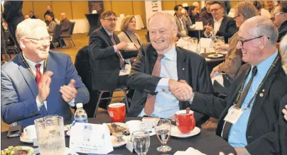  ?? CHRIS SHANNON/CAPE BRETON POST ?? Former prime minister Jean Chrétien shares a laugh and a handshake with Membertou Chief Terry Paul, right, as Cape Breton Regional Municipali­ty Mayor Cecil Clarke applauds, while an image of Chrétien and Paul appears on the big screen showing the mock...