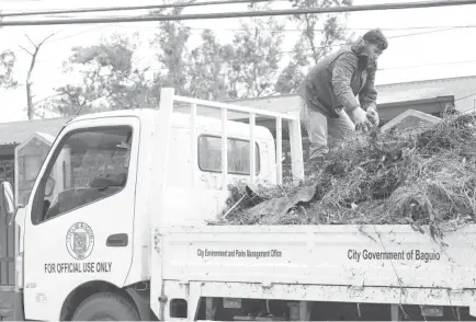  ?? Photo by Jean Nicole Cortes ?? CLEAN-UP. Workers from the City Environmen­t and Parks Management Office round up garbage at the Baguio Public Cemetery after the All Saints and All Souls day commemorat­ion.