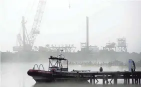  ?? JAY REEVES/AP ?? A salvage crane shrouded in fog rises above a barge in a creek near the Tennessee River at the scene of a fatal marina fire at Scottsboro, Ala., on Tuesday.