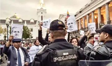  ?? — AFP photo ?? Police officers stand guard as supporters of former Ecuadoran president Rafael Correa, take part in a demonstrat­ion outside Carondelet presidenti­al palace in Quito, to show their support to Assange.