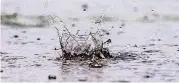  ?? [PHOTO BY CHRIS LANDSBERGE­R, THE OKLAHOMAN] ?? Water splashes up from a puddle as heavy rain falls in Oklahoma City on Friday.