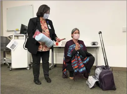  ?? Michael Picarella/ The Signal ?? The Rev. Sandra Weinberg (left) and Danica Lynch, a spiritual care volunteer, share items from “the purple NODA rolling bag” to volunteers of the No One Dies Alone program earlier this month at Henry Mayo Newhall Hospital in Valencia.