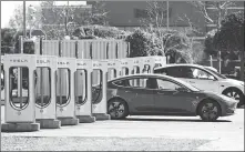  ?? JUSTIN SULLIVAN / GETTY IMAGES ?? The battery of a Tesla car is recharged in Petaluma, California, this month. With oil prices continuing to soar, shares of companies in the electric vehicle sector are rising.