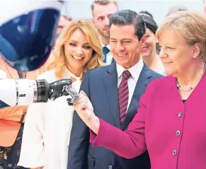  ?? FOTO: RTR ?? Kanzlerin Merkel zeigt einem Roboter der sauerländi­schen Firma IGB Automation die Faust. Mexikos Präsident Enrique Peña Nieto und seine Frau Rivera schauen zu.