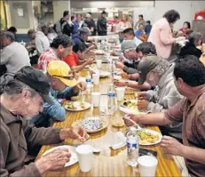  ??  ?? HOMELESS MEN, most of them Latinos who lack legal status, share a meal at a facility that also offers shelter in Los Angeles.