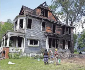  ?? RICK WOOD / MILWAUKEE JOURNAL SENTINEL ?? Workers on June 24 clean up a duplex in the 2100 block of North 40th Street that was set on fire the day before as hundreds of people gathered where police earlier conducted an investigat­ion into two missing teenage girls.