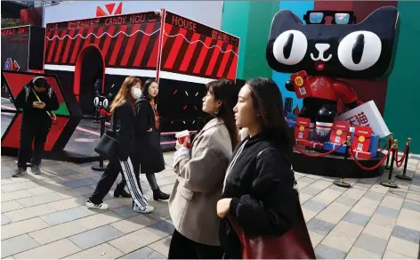  ?? NG HAN GUAN/AP ?? Shoppers walk by a promotion in Beijing on Wednesday by Alibaba’s Tmall online shopping platform for the upcoming Singles’ Day. Alibaba is looking to break another sales transactio­n record Sunday after a decade of exceeding prior results with its shopping celebratio­n