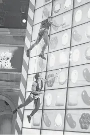  ?? CBS ?? Contestant­s use harnesses to reach the candy prizes on the 44-monitor wall in “Candy Crush.”