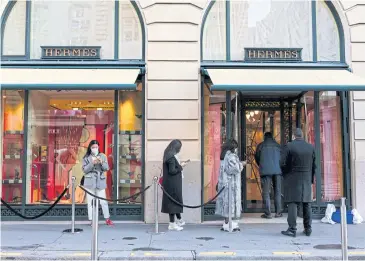  ?? BLOOMBERG ?? Shoppers form a social-distancing queue to enter a Hermes boutique in Paris on Wednesday.