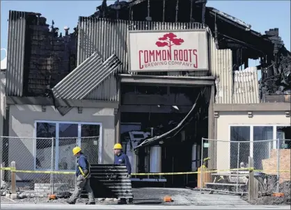  ?? Photos by Will Waldron / Times Union ?? Workers on Tuesday remove debris from the Commons Roots Brewing Co. in South Glens Falls after Monday’s fire. The father-and-son team of Bert and Christian Weber started the business in 2014.