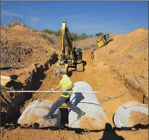  ?? Arkansas Democrat-Gazette/STEPHEN B. THORNTON ?? Lee Davidson leaps over newly installed drainage pipes in November during work on the Arkansas River levee near Bigelow in Perry County. The levee was the scene of flooding in December 2015, and a recently revived levee board is spending more than...