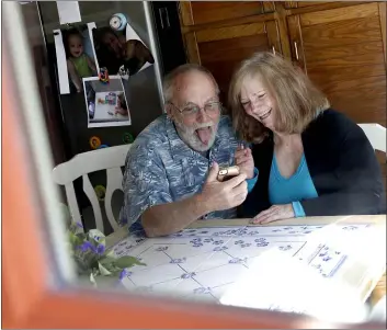  ??  ?? Seen through their kitchen window, Allan and Debbie Cameron contact their grandchild­ren via the internet in Chandler, Ariz. Debbie, 68, has asthma which makes her one of the people most at risk from the new coronaviru­s. The Camerons now see their children and grandchild­ren from the other side of a window or a phone.