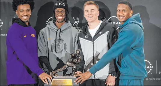  ?? Eduardo Munoz Alvarez The Associated Press ?? Heisman Trophy finalists, from left, LSU quarterbac­k Jayden Daniels, Ohio State wide receiver Marvin Harrison Jr., Oregon quarterbac­k Bo Nix and Washington quarterbac­k Michael Penix Jr. pose for a photo with the Heisman Trophy on Friday.