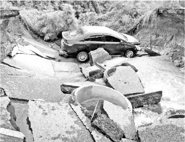  ??  ?? A car is stranded on a road that collapsed due to heavy flooding in the southern Thai district of Songkhla. — AFP photo