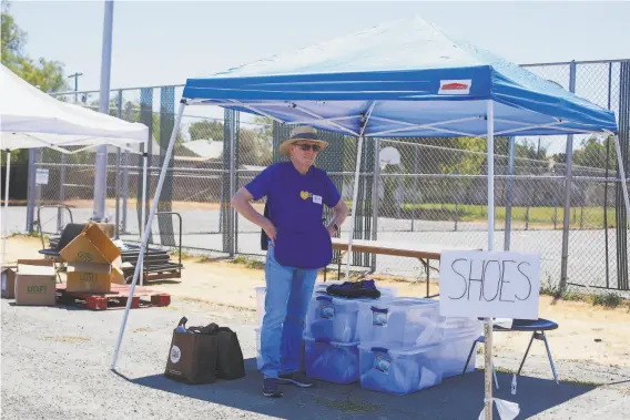  ??  ?? Jim Piepergerd­es helps out during a giveaway of clothes. White Pony Express recovers clothing — unsold, brandnew overstock, outofseaso­n and returns.